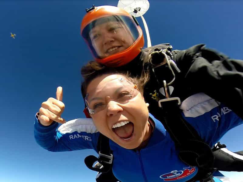 Anna thumbs up in freefall with Tandem Master Sara