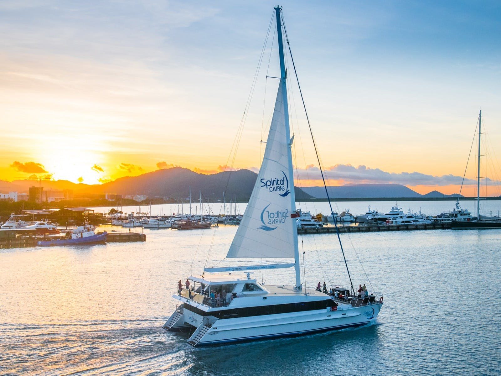 Spirit of Cairns catamaran sailing down Trinity inlet with sunset and mountains in the background