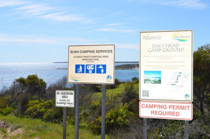 Bush Campground Signs - Permit Required. Ocean view in background.