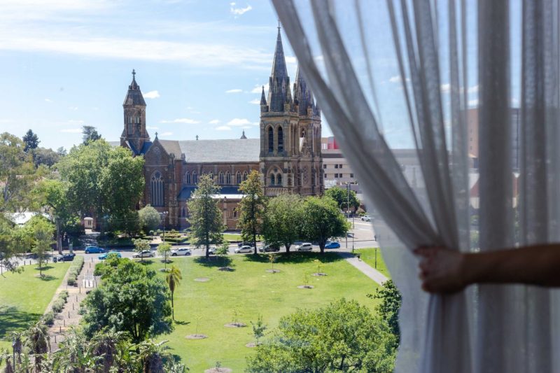 Oval Hotel curtain pulled back to reveal views of parkland and St Peter's Cathedral