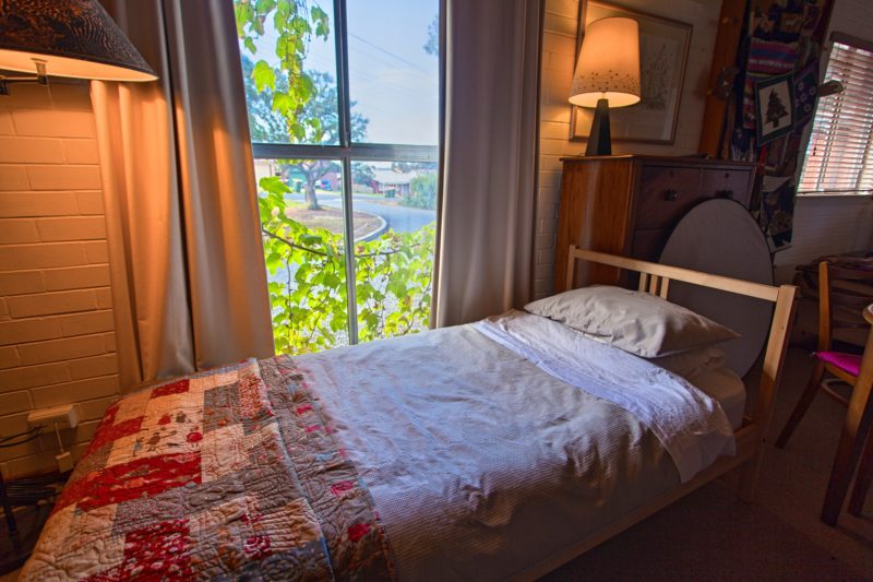 Single bed with quilt bedspread and window view of front garden and parking