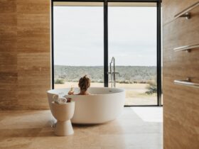 Woman sitting in round bath looking out at bushland view