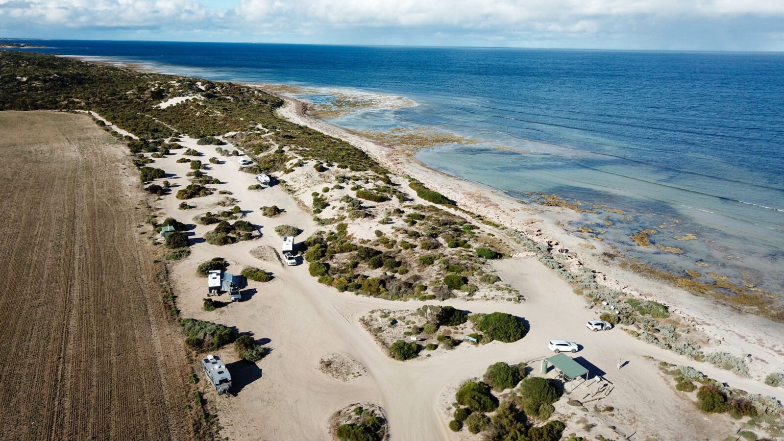 Drone view of sand track campsites, beach and aqua ocean, horizon