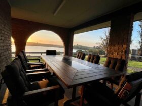 Outdoor dining table with 8 seats and sunset view over the lake.
