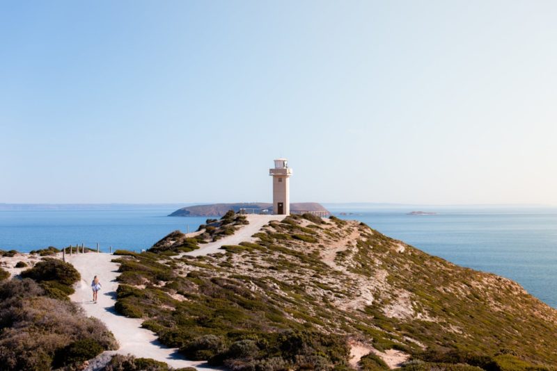 A wide shot of Cape Spencer lighthouse and the with sandy path that leads to it.