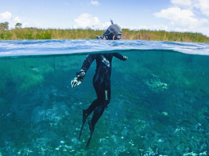 A diver floats with their head above the water.