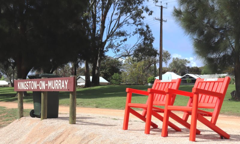 A pair of #riverredchairs sits next to the sign welcoming houseboats to the riverfront.