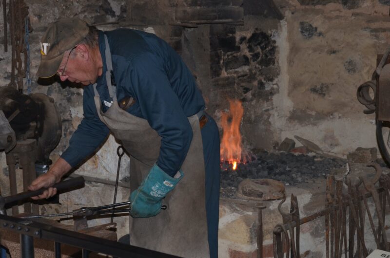 A blacksmith in action at one of the working forges.
