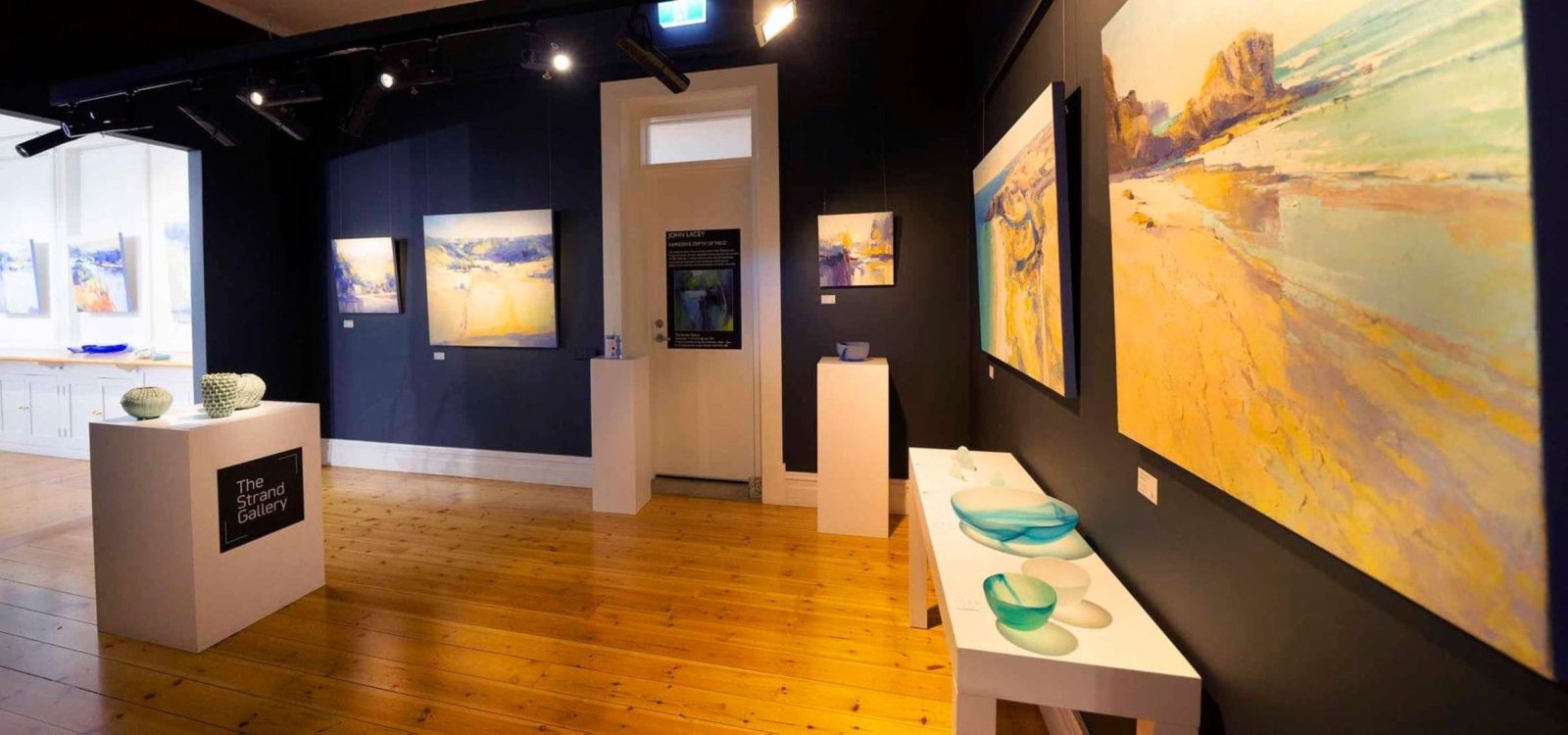 gallery interior showing dark painted walls and artwork hanging