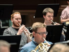 3 brass instrumentalists playing in an orchestra