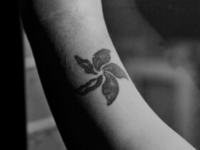 A photograph of an arm with a black tattoo of a flower