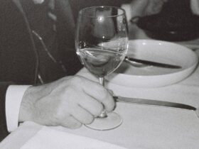 Man holds glass of white wine at dinner table