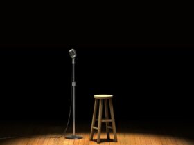 A cartoon microphone on a stand on the left of a wooden stool.