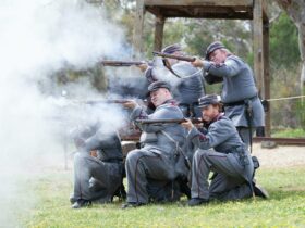 6 Victorian dressed soldiers firing muskets with plumes of smoke