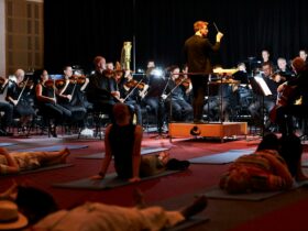 People sit on yoga mats as they watch an orchestra