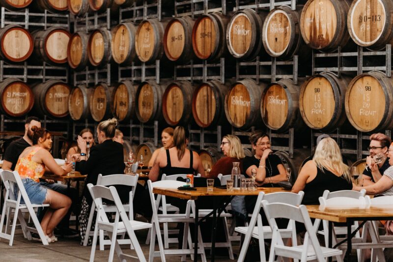 People drinking wine in barrel warehouse
