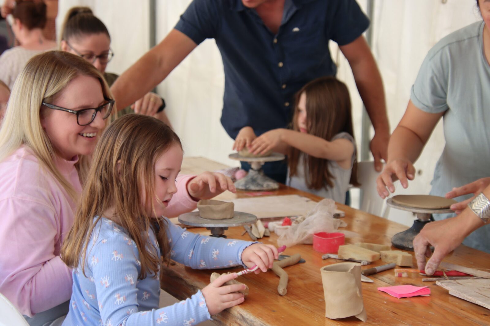 An adult and child works together to make a bowl or cup out of clay