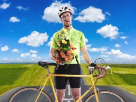 A man wearing lycra holds flowers and stands by his bike looking tired