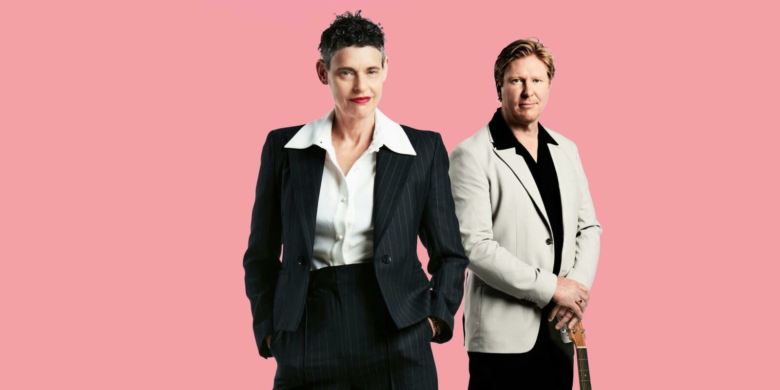 Deborah Conway and Darren Coggan standing in front of a pink background