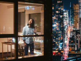 A man in a high-rise apartment looks up to the night sky