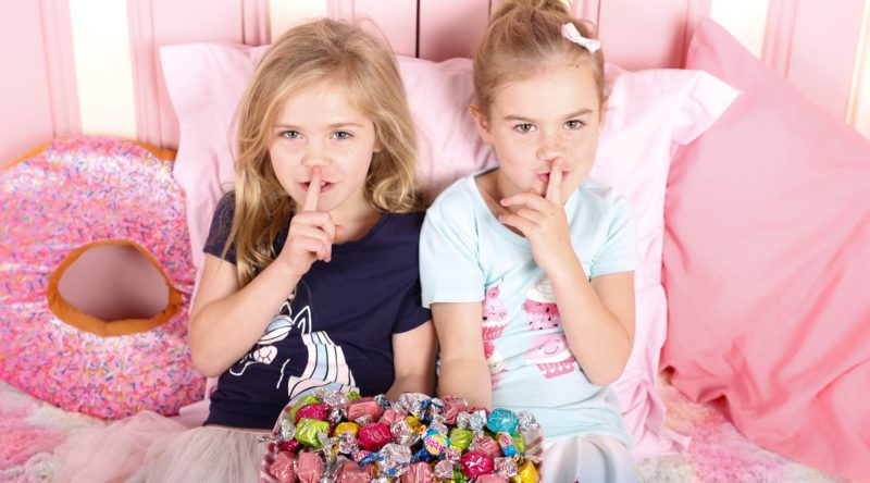 Shhhhh... Girls in bed with stash of lollies