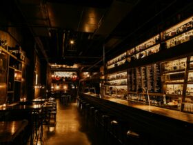 A spanning image of the bar, low lit and wood finishings.