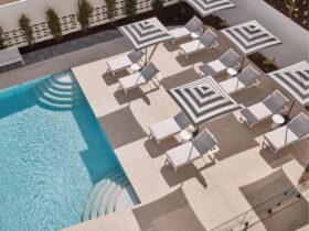 The pool at ela with striped umbrellas and lounge chairs