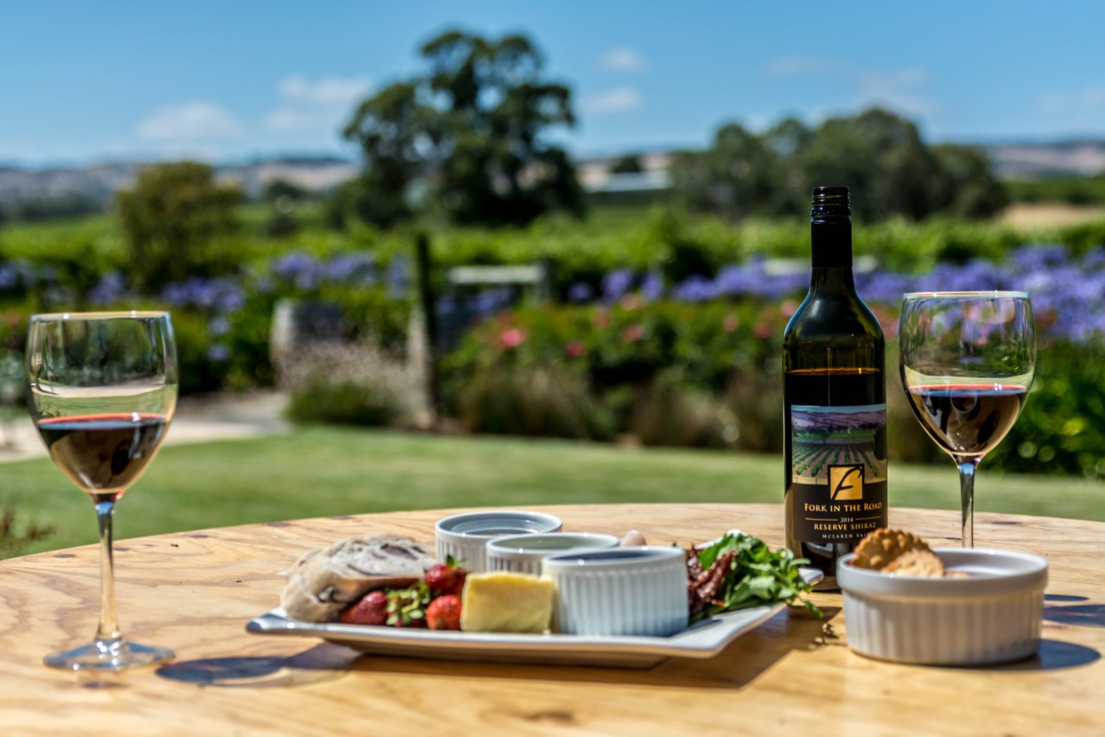 A bottle of our wine, with two glasses poured and one of our regional platters on offer.