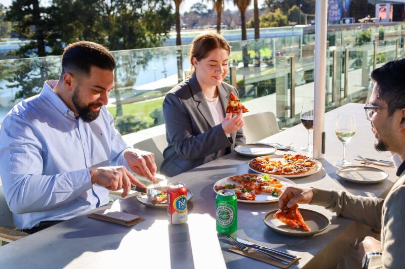 People at a table enjoying pizza on the Adelaide Riverbank at Home Ground