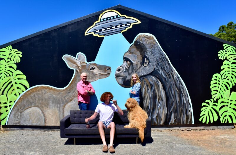 A piece of wall art featuring a kangaroo and a gorilla in the beam of a flying saucer