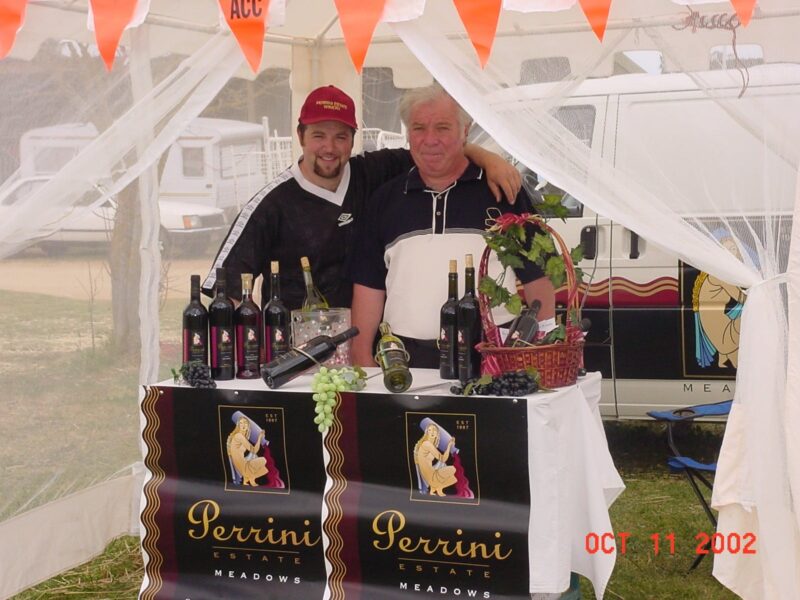 Happy Perrini owner and one other displaying wines