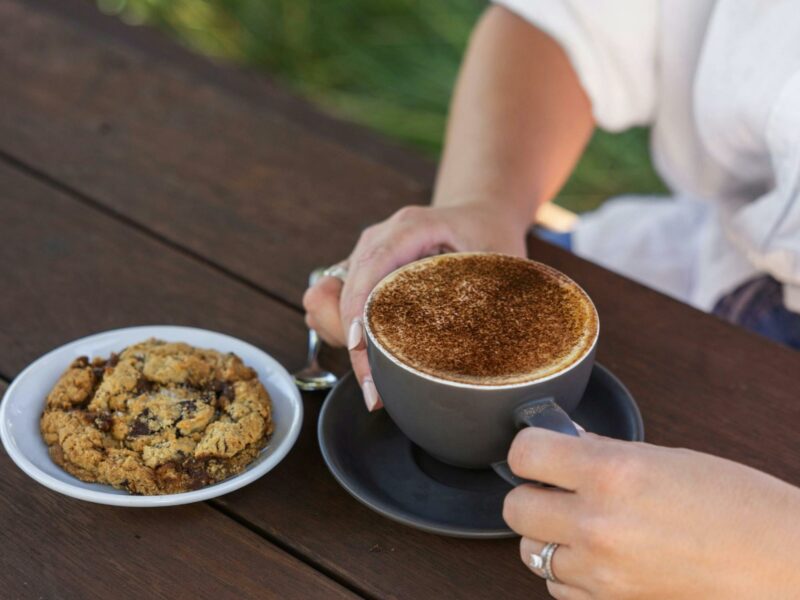 Woman enjoying a cappuccino and cookie at Bean Addiction.