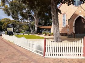 beautiful old church with a white picket fence and a large gum tree