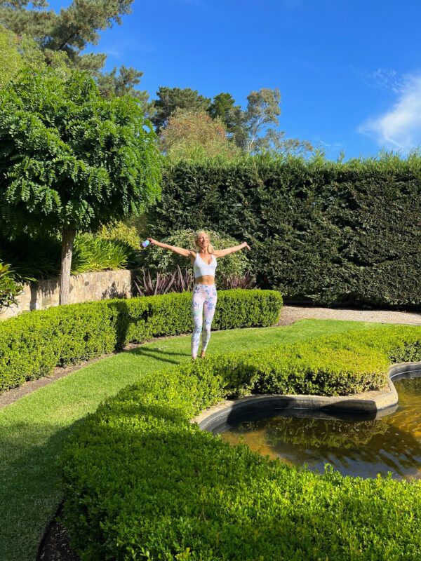 Nikki welcoming the sun in nature around lush green surroundings