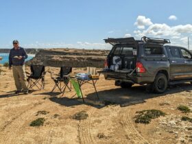 People standing by a 4WD vehicle having lunch at the top of coastal cliffs.