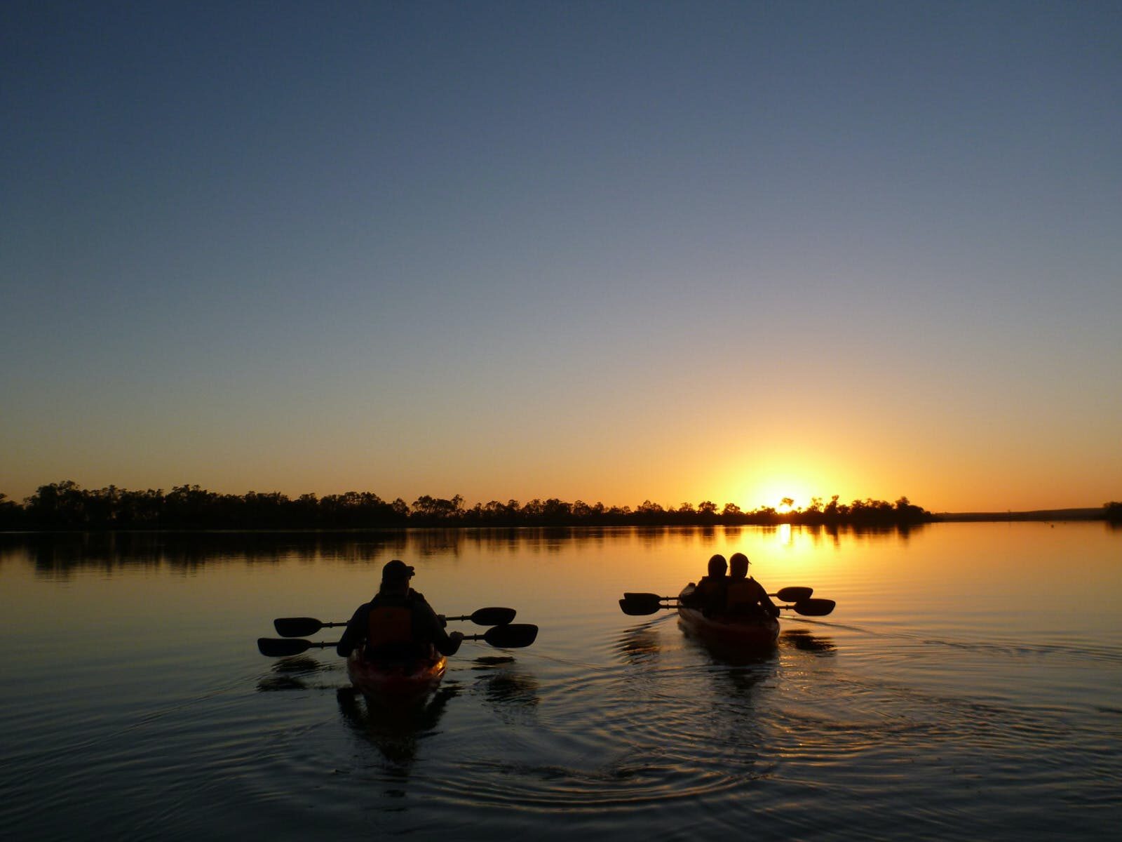 2 silhouetted kayaks in the glow of sunrise.