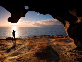 A man stands under the arch of the remarkable rocks