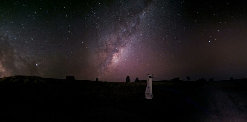The Milky Way is rising in the background with a telescope in the foreground