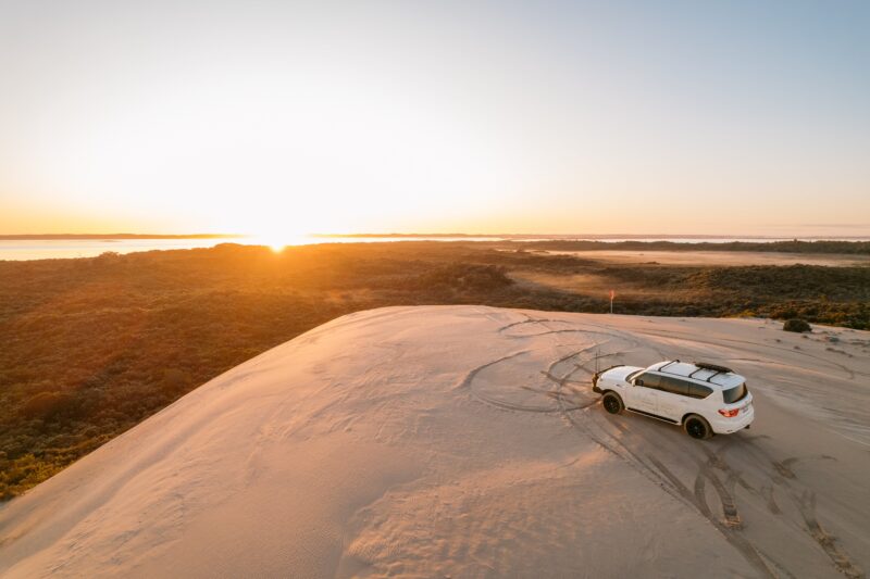 Tour vehicle parked on large dune over looking Lake George on sunrise