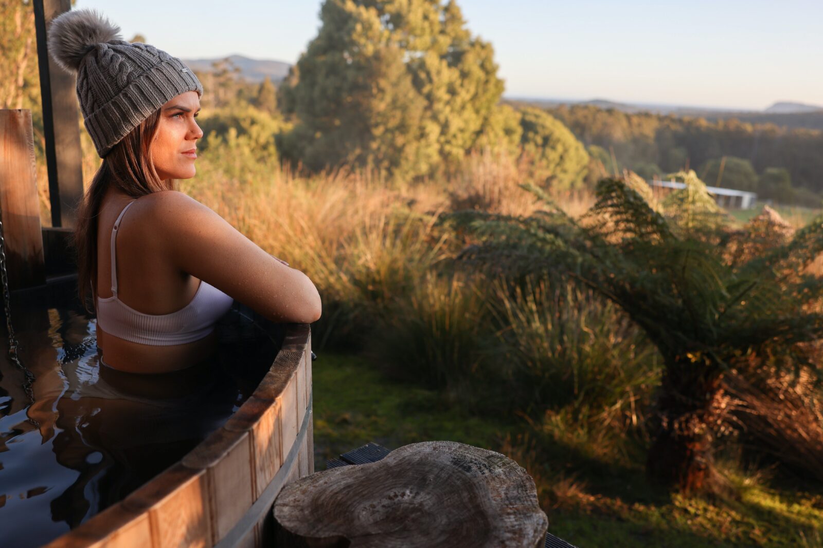 Lady relaxing in barrel hot tub facing out to Cloudy Bay