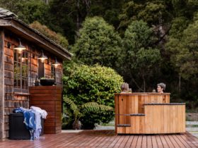 Photograph of a hot tub, with two women sitting in it. The hot tub sits on a wooden deck