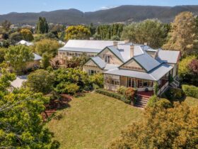 A large, historic weatherboard home within landscaped grounds. The building looks well maintained.