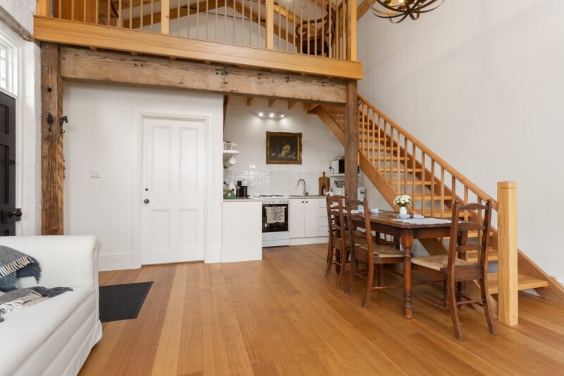 wooden floors in downstairs lounge dining area showing wooden stairs leading to loft bedroom