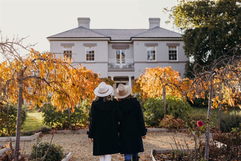 Two persons walking through autumn leaved garden toward the entrance of Prospect House.