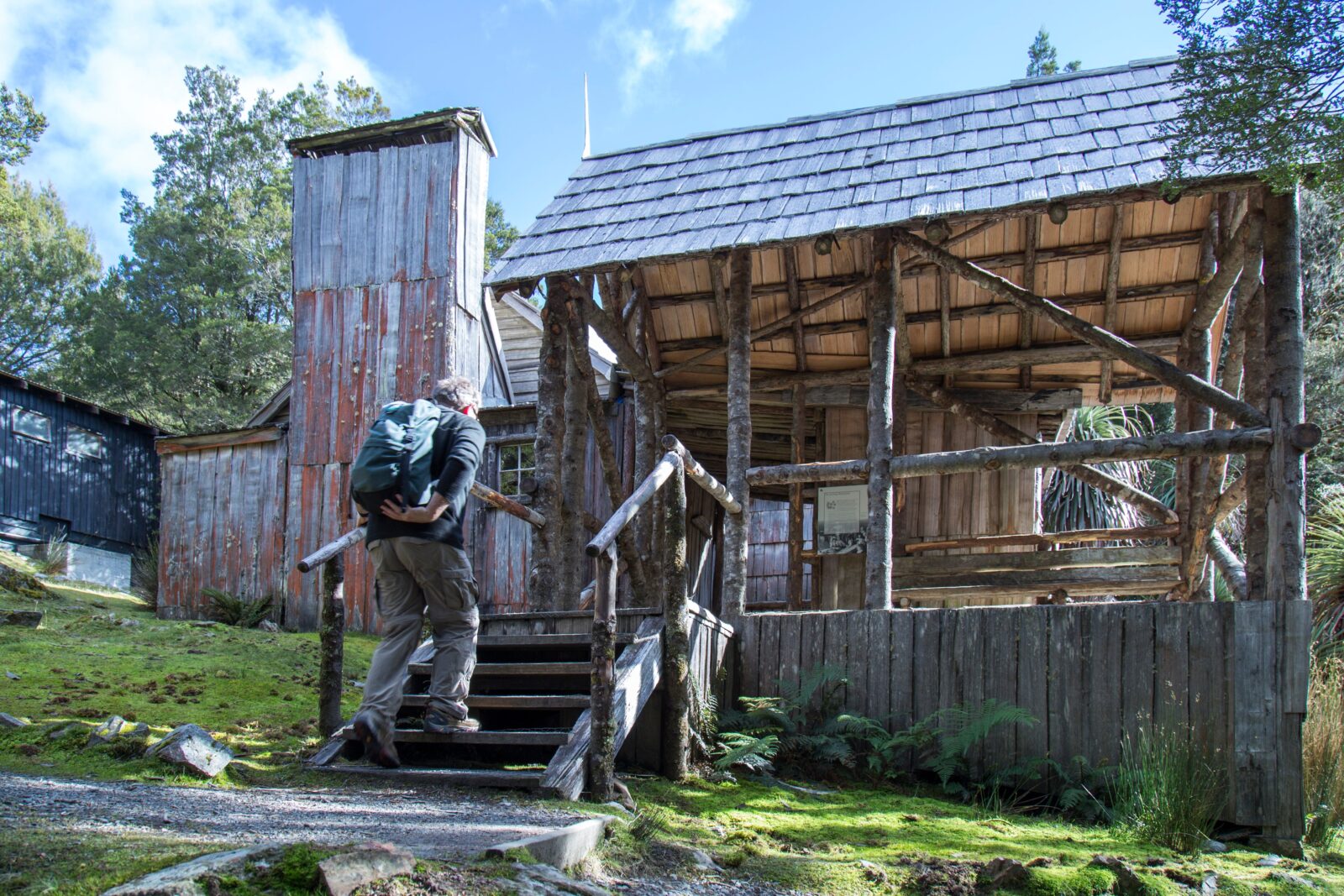 A man walking up the steps of an old cabin