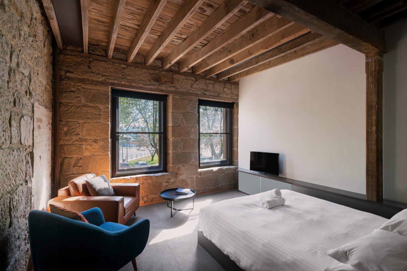 Bricked-over escape passage, sandstone walls, exposed beams, armchairs, king size bed, TV