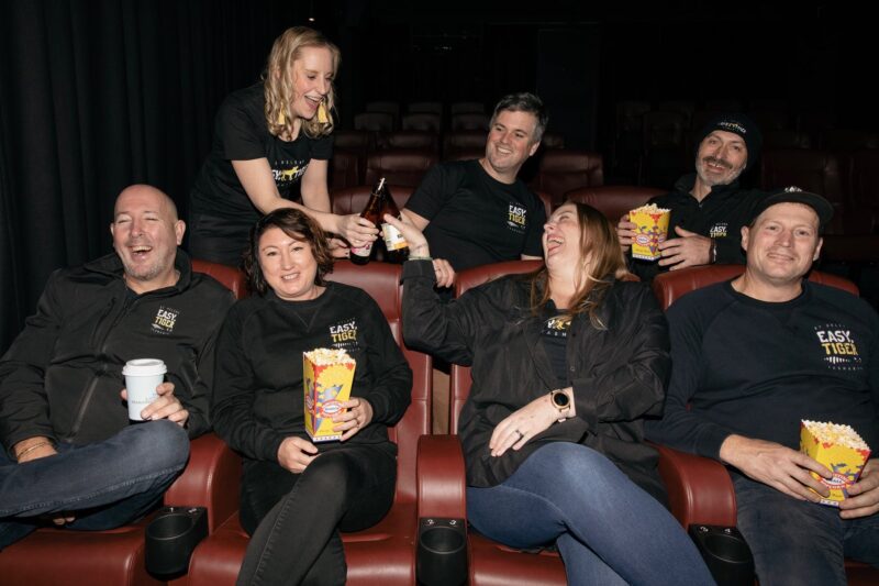 Easy Tiger Cinema St Helens owners in the cinema enjoying popcorn and drinks, laughing and joking
