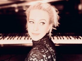 A portrait photograph of Jude Elliot sitting in front of a piano