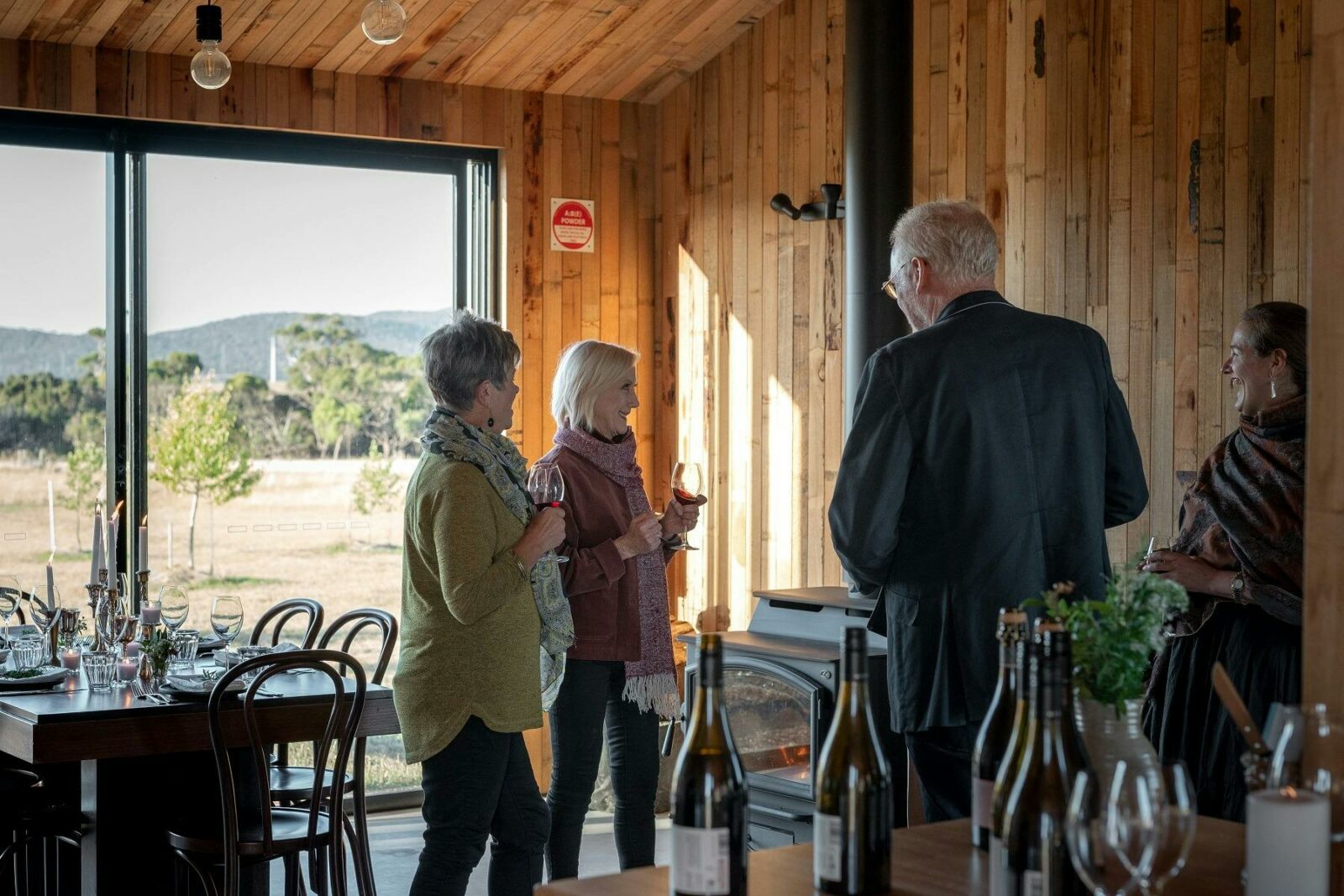 Westella Vineyard. Four guests are holding wine glasses and they are talking to each others.