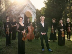 Performers from VDB pose with their instruments in front of an old church
